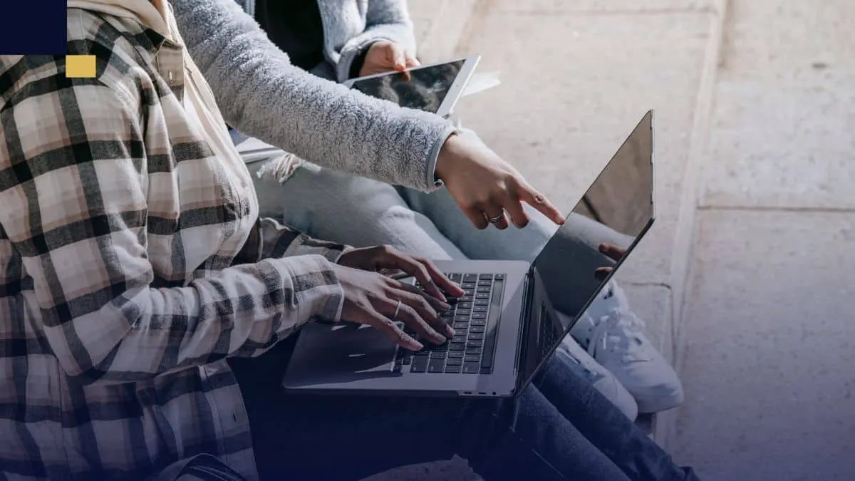 Estudiantes colaborando en laptop y tablet para investigar tipos de investigación académica