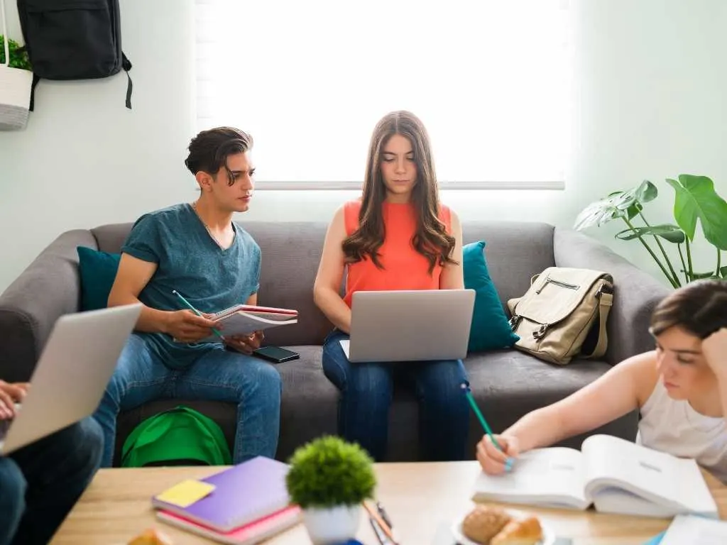 Grupo de estudiantes universitarios trabajando juntos en una sala de estudio, colaborando en el diseño y análisis de una investigación correlacional.