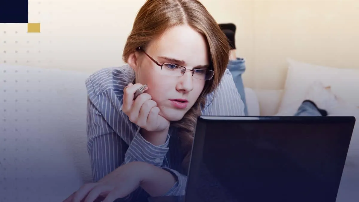 Joven estudiante recostada usando laptop, investigando y redactando resultados de un estudio correlacional desde casa.